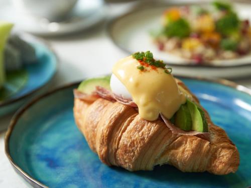 バンコクにあるパーク ハイアット バンコクの青い皿にチーズとピクルスを乗せたクロワッサン