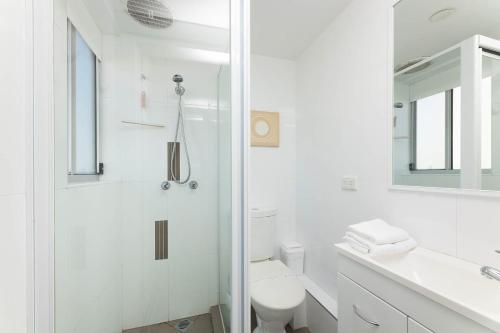 a white bathroom with a shower and a toilet at El Sandi Unit 7 in Forster