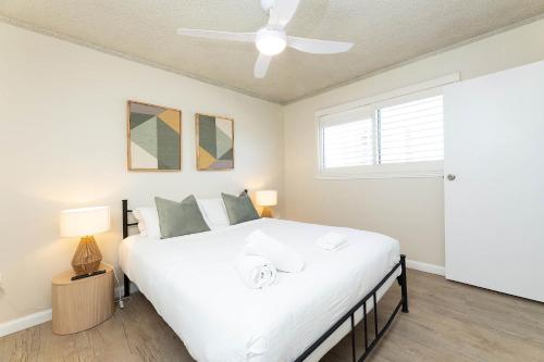 Un dormitorio con una cama grande blanca con ventilador de techo. en El Sandi Unit 7, en Forster