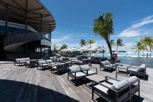a resort patio with lounge chairs and a pool at Madifushi Private Island in Meemu Atoll