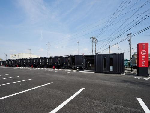 ein leerer Parkplatz mit einer Reihe schwarzer Behälter in der Unterkunft HOTEL R9 The Yard Kaizu in Kaizu