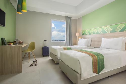una camera d'albergo con due letti, una scrivania e una finestra di KHAS Pekanbaru Hotel a Pekanbaru