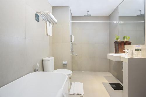 bagno bianco con servizi igienici e lavandino di KHAS Pekanbaru Hotel a Pekanbaru