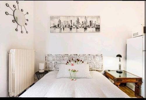 Un dormitorio con una cama blanca con una mesa y una foto en Relax a 4 salti dai navigli, en Milán