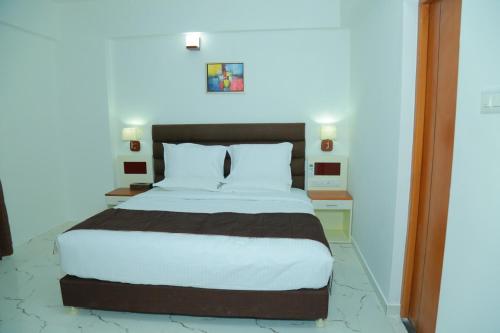 a bedroom with a large bed with white sheets at Utsavam Hotel Apartments in Guruvāyūr