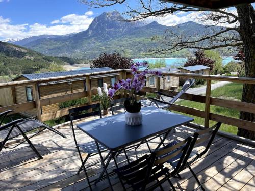 a table with a vase of flowers on a deck at Mobil-Home Baie Saint-Michel, Serre-Ponçon in Chorges