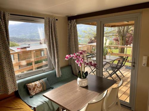 a dining room with a table and a balcony at Mobil-Home Baie Saint-Michel, Serre-Ponçon in Chorges