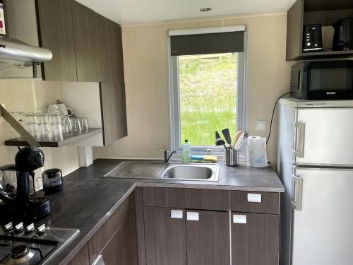 a kitchen with a sink and a white refrigerator at Mobil-Home Baie Saint-Michel, Serre-Ponçon in Chorges