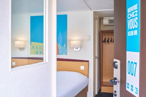 a small room with a bed and a mirror at Kyriad Direct Le Havre Est - Gonfreville in Gonfreville-lʼOrcher