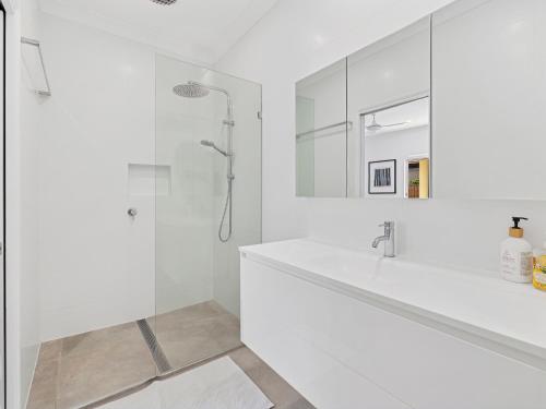 een witte badkamer met een wastafel en een douche bij Parkside Noosa River in Noosaville