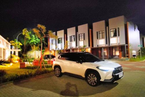 a white suv parked in front of a building at night at Freja House @ Central BSD in Samporo