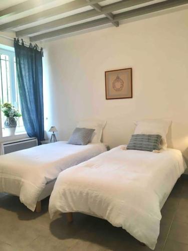 two beds in a white room with a window at Cottage de charme à la campagne in Aulnoy