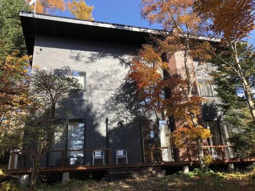 a house with two chairs in front of it at 木漏れ日ハウス in Karuizawa