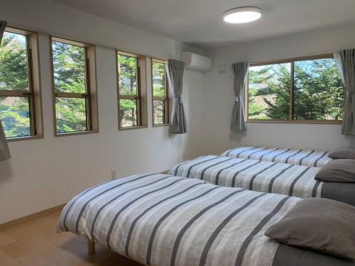 three beds sitting in a room with windows at 木漏れ日ハウス in Karuizawa