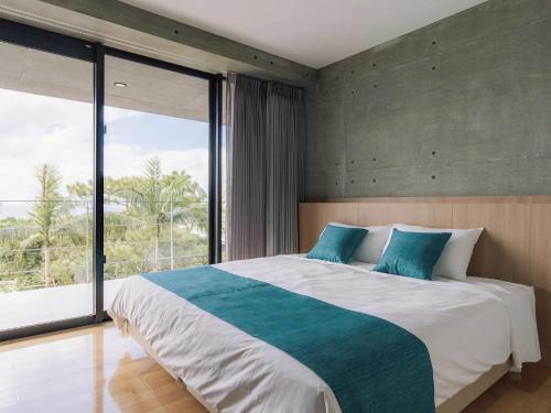 Bosco Yomitan Resort Condminium في يوميتان: غرفة نوم بسرير كبير ونافذة كبيرة