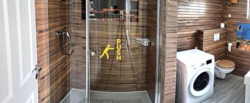 a shower in a bathroom with a washing machine at Zimmerferi Apartman Keszthely in Keszthely