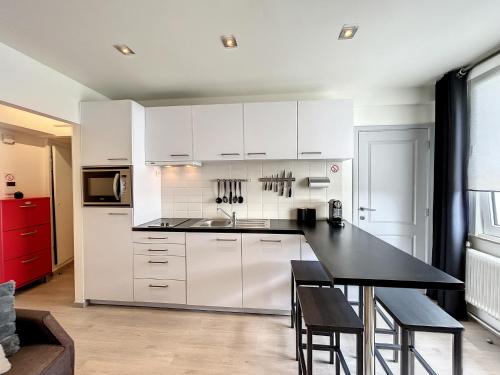 a kitchen with white cabinets and a black table at Vakantieverblijf Monopole Oostende in Ostend