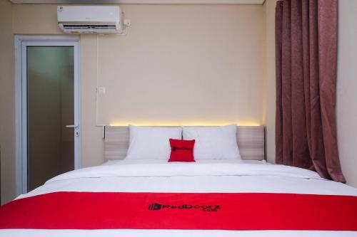 uma almofada vermelha sentada em cima de uma cama em RedDoorz Plus near RS JIH Solo em Surakarta