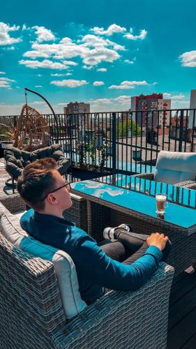 a man sitting in a wicker chair next to a pool at Seven Hotel Bytom - Katowice in Bytom
