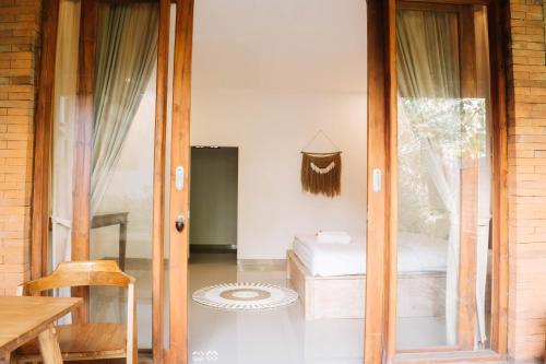 a room with a bed and a sliding glass door at Bramasa Ubud Guest House in Ubud