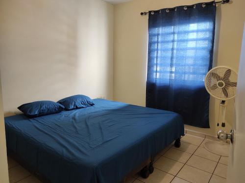 Tu casa en Mazatlan. في مازاتلان: غرفة نوم بسرير وملاءات زرقاء ومروحة