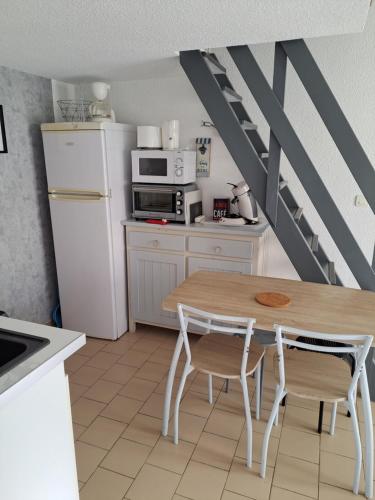 une petite cuisine avec une table et un réfrigérateur dans l'établissement Maisonnette, 5 Pers, 500m plage, Parking, Terrasse, au Cap d'Agde