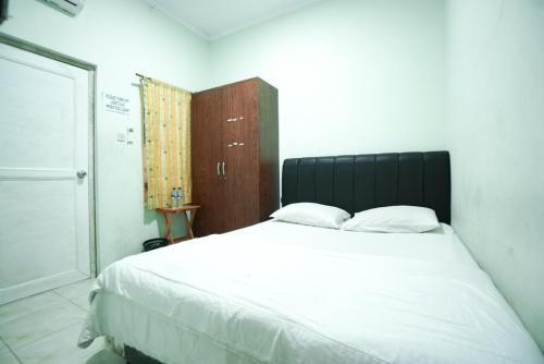 1 dormitorio con 1 cama blanca grande y 2 almohadas en Mahkota Sivali near Soekarno Hatta Airport Mitra RedDoorz, en Tangerang