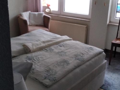 a bedroom with a bed and a chair and a window at Pension Schulze in Oranienbaum-Wörlitz
