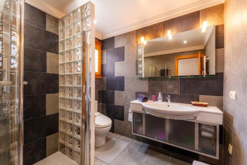 een badkamer met een wastafel, een toilet en een spiegel bij Na Forana Cala Ratjada in Cala Ratjada