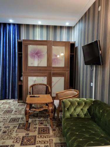 uma sala de estar com um sofá e uma televisão em seoul hotel em Shymkent