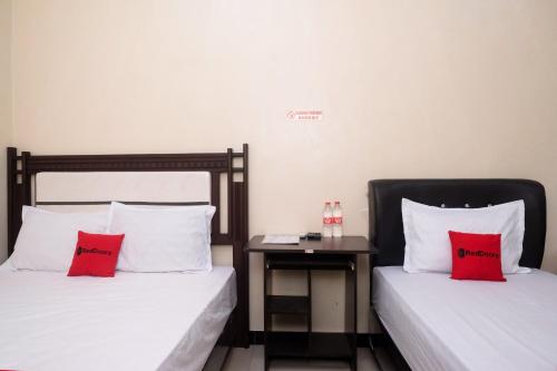 2 Betten mit roten Kissen in einem Zimmer in der Unterkunft RedDoorz Syariah near Flyover Palur in Karanganyar