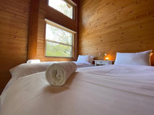 a bedroom with two beds with wooden walls and two windows at Haus Yuki in Hakuba