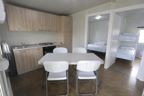 cocina con mesa blanca y sillas blancas en Tropical Casette Residence, en Diamante