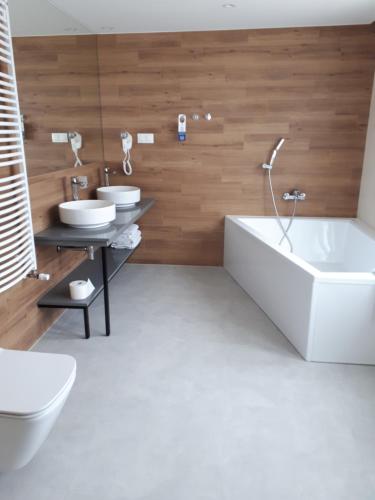 uma casa de banho com 2 lavatórios, uma banheira e um WC. em Halo Toruń em Toruń