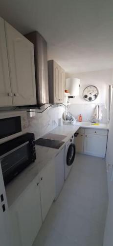 une cuisine avec des armoires blanches, un évier et un lave-vaisselle dans l'établissement Studio cosy à Nice, à Nice