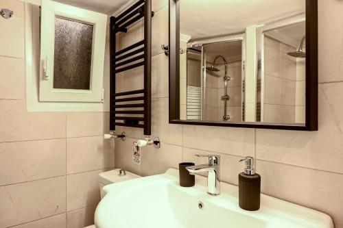 ein Badezimmer mit einem Waschbecken, einem Spiegel und einem WC in der Unterkunft Thessaloniki Center Deluxe Apartment in Thessaloniki