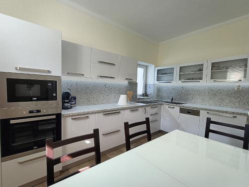 a kitchen with white cabinets and a table and chairs at Zimmerferi Apartman Keszthely in Keszthely