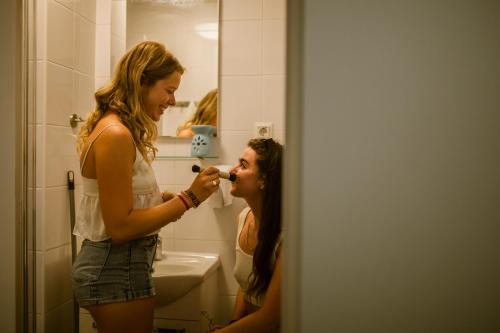 Een vrouw die in de badkamer haar tanden poetst. bij Booze & Snooze Social Hostel in Split