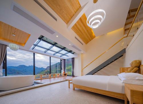 ein Schlafzimmer mit einem Bett und einem großen Fenster in der Unterkunft Drunken Valley Manor - Zhangjiajie National Forest Park in Zhangjiajie