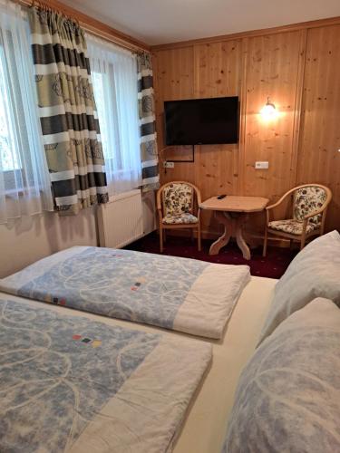a hotel room with two beds and a table and a tv at Berggasthof Hintergföll in Unken