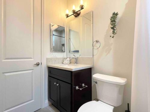 a bathroom with a toilet and a sink and a mirror at Charming 3B3B Townhome (Relax & Family Friendly) in Pasadena