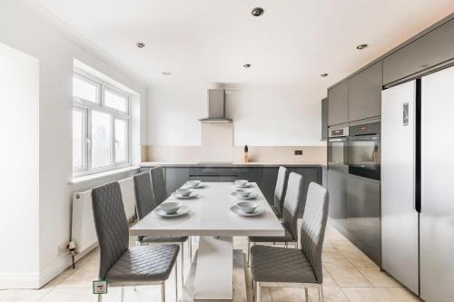 a kitchen with a white table and chairs in a room at Surrey Stays - 4 bedroom house, sleeps 9, 2 bathrooms, CR5, near Gatwick Airport in Banstead