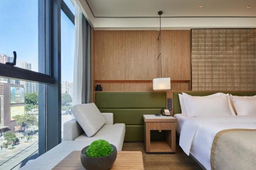 a hotel room with a bed and a couch and a window at Dongguan Tangxia Huaman Hotel in Dongguan