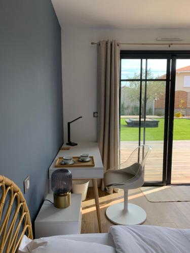 une chambre avec un lit, un bureau et une chaise dans l'établissement Le Jardin 51, à Andernos-les-Bains