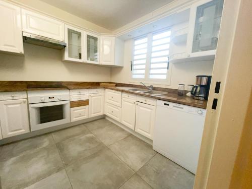 - une cuisine avec des armoires et des appareils blancs dans l'établissement L'Hermitage - Appartement T3 en bord de plage, à Filaos