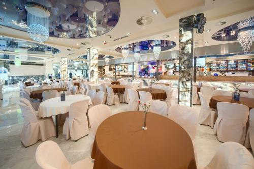 ヤロスワビエツにあるAquapark Health Resort & Medical SPA Panorama Morska All Inclusiveの白いテーブルと白い椅子が備わるレストラン
