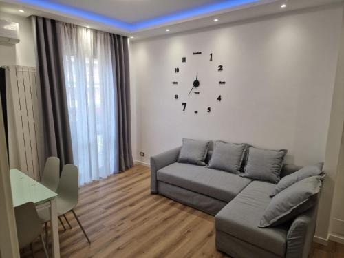 uma sala de estar com um sofá e um relógio na parede em Residence Laura em Cesano Boscone