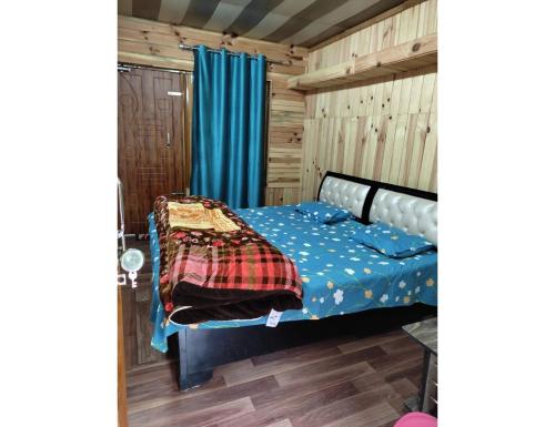a bedroom with a bed with blue sheets and blue curtains at Sandeep Home stay, Chakrata in Chakrāta