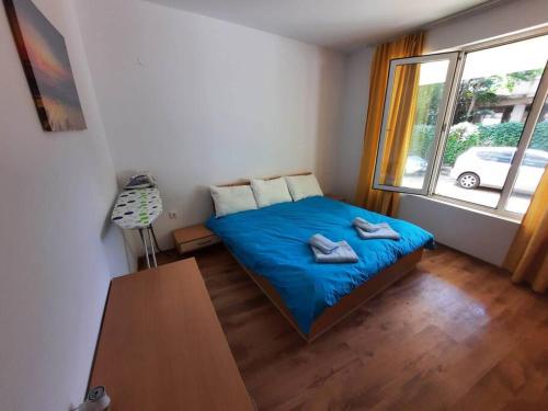 een slaapkamer met een bed met blauwe lakens en een raam bij Central, 1 Bed Apt, 3* Yassen in Sunny Beach