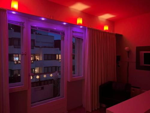 ベルリンにあるCozy Modern Apartment with Small Balcony in the Heart of Berlinの紫色の照明が付いた窓のある部屋